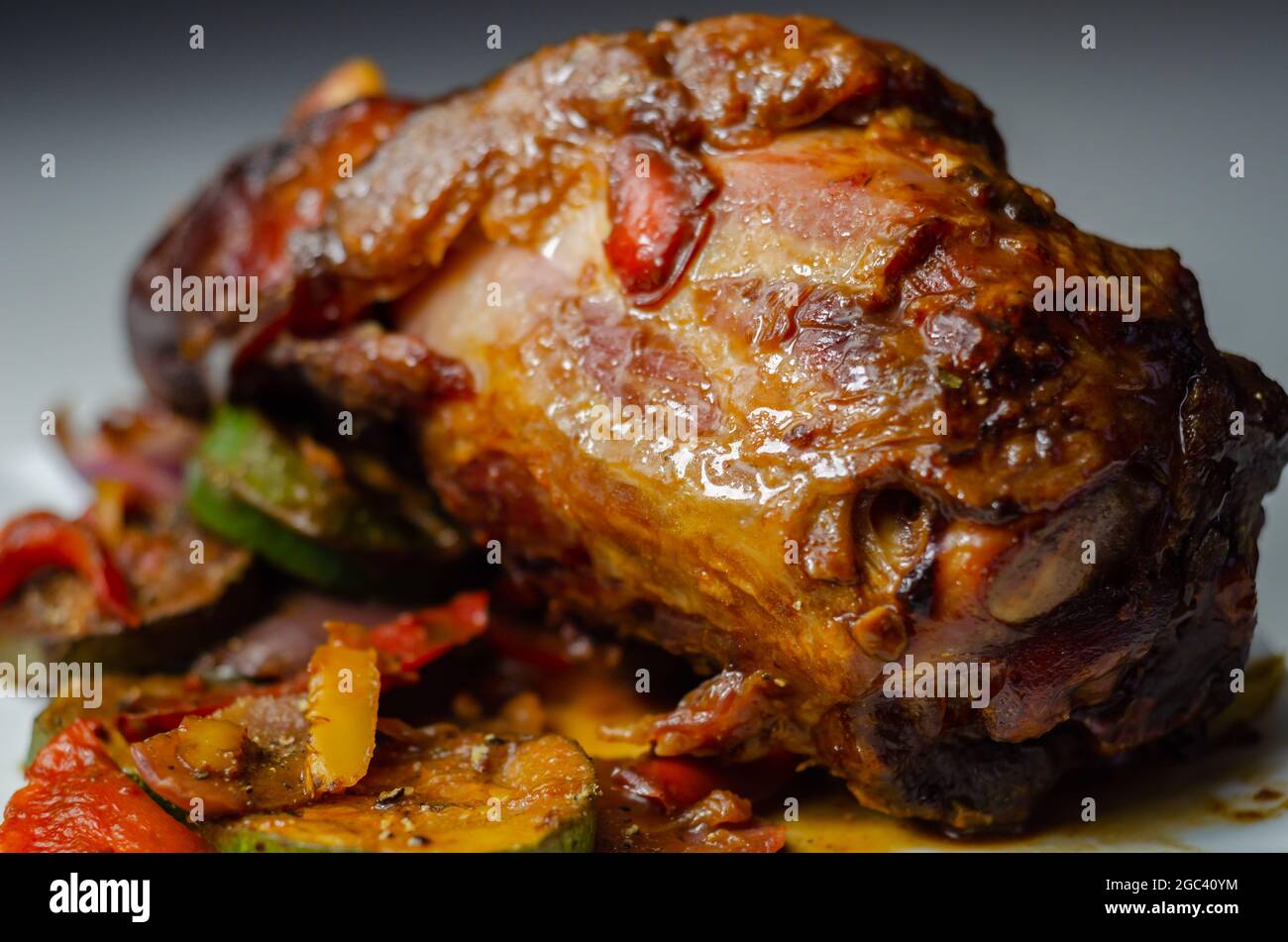 Bacon joint with bone served with grilled vegetables, red and yellow