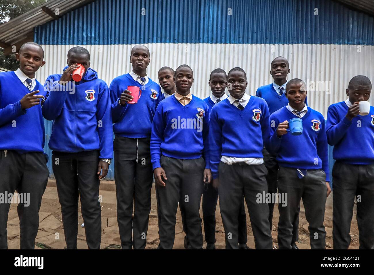 The 18-year-old Saviour Omondi, a local artist (C) takes a photo with his school mates outside his school compound in Raila Educational Centre in Nairobi.An 18-year-old artist born and raised in Kibera, from a family of five, he began his love for art back in 2009 by copying and learning most skills from his dad who was doing art but not to a professional level. Omondi’s main focus was to portray his home through his artwork and dreamt of making the best out of his art in the future after his studies. Stock Photo