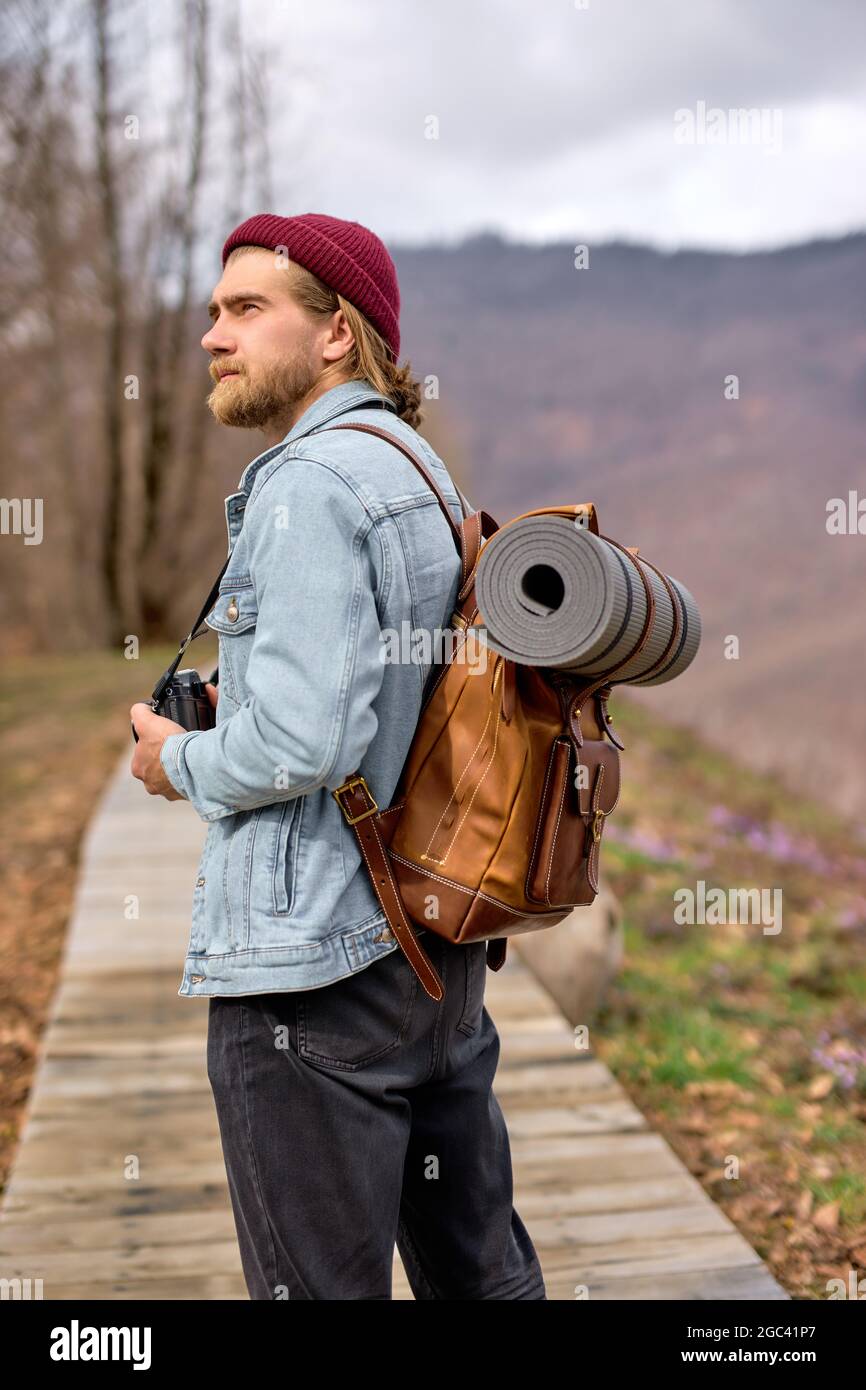Young man with brown backpack exploring nature in spring, walking
