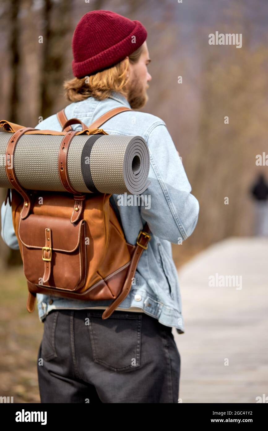 man with brown backpack exploring nature in spring, walking alone