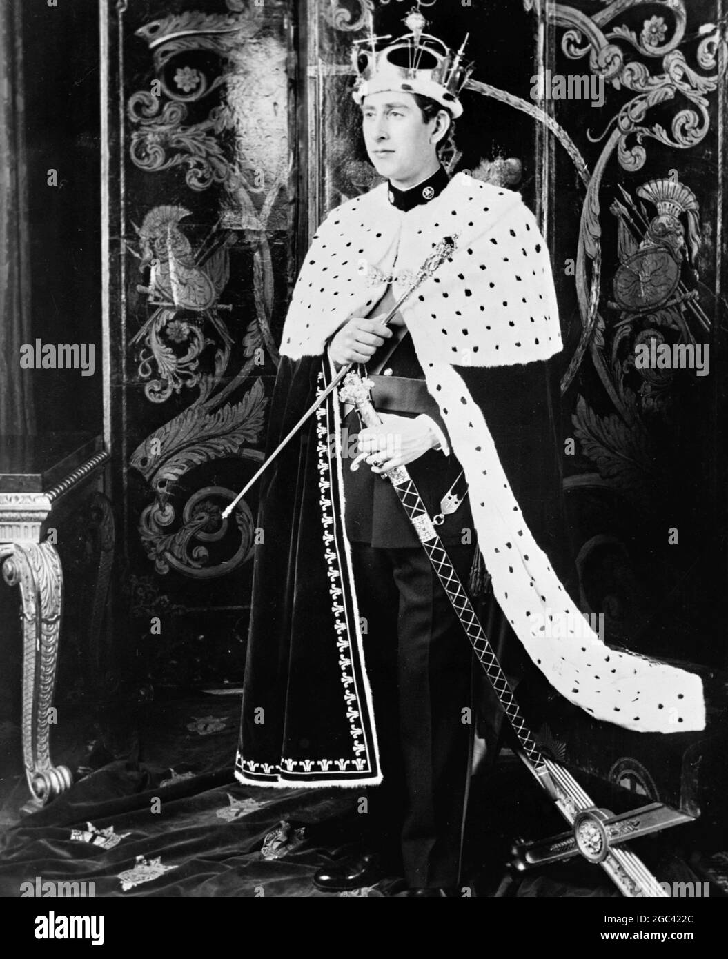 The official picture of Prince Charles, who will become the Prince of Wales, at a ceremony to be performed by Her Majesty Queen Elizabeth II at Caernarvon Castle, Wales on 1 July 1969. The Prince of Wales, pictured by Norman Parkinson at Windsor Castle, Berkshire is wearing his full regalia. Over a military uniform he wears an ermine robe. On his head is the Gold Coronet, weighing 3lbs and containing 75 diamonds and 12 emeralds. In one hand he carries the Gold Rod; in the other, the Sword of Office. 25 June 1969 Stock Photo