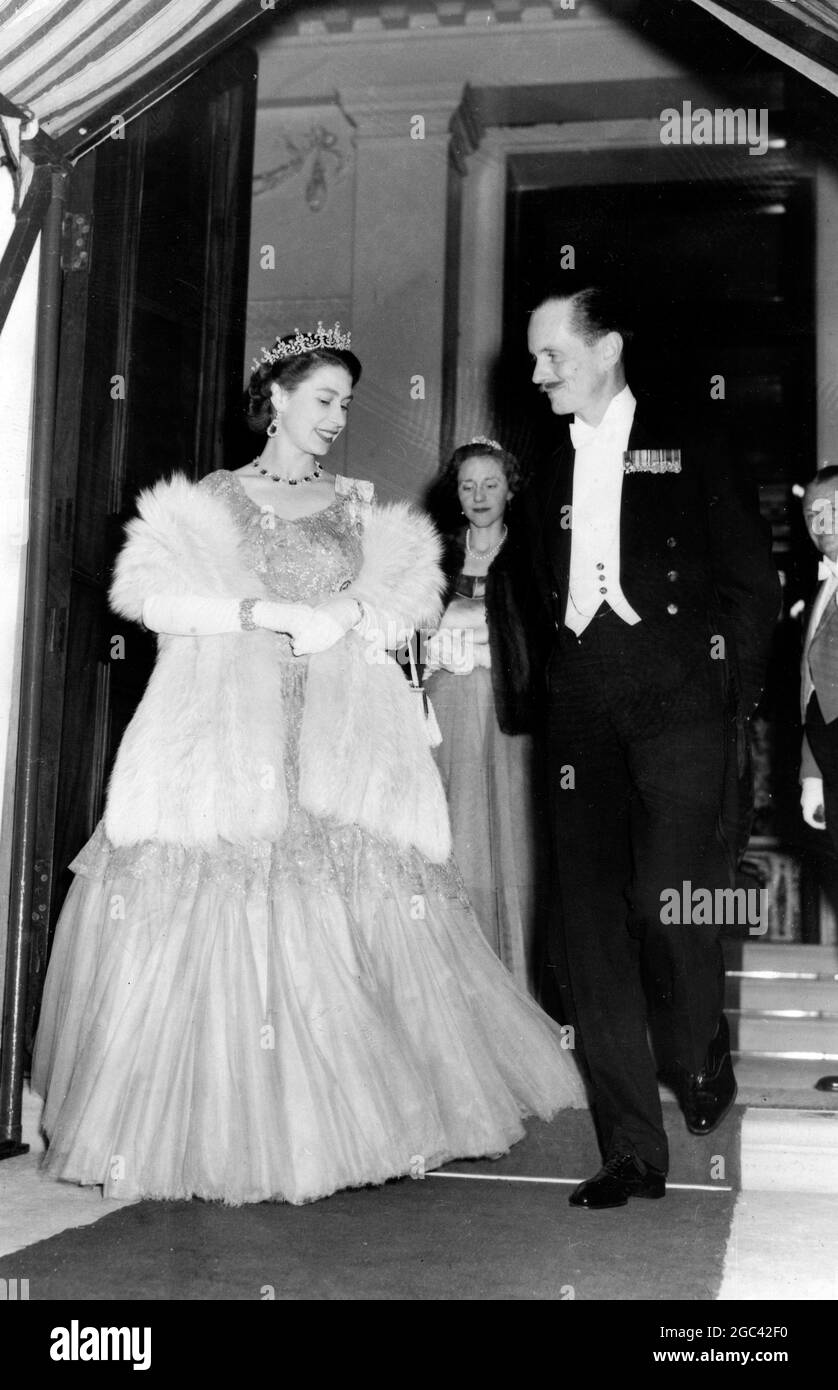 The Queen leaves after the ball London : The Queen , in a gown of silver brocade and wearing a diamond necklace and a diamond and emerald tiara , pauses to chat with the Earl of Leicester as she leaves Londonderry Hosue where she attended her first ball of the season. The party was the coming-out ball for Lady Annabel Stewart , daughter of the Marquess of Londonderry , and Lady Carey Coke , daughter of the Earl of Leicester 9 July 1952 Stock Photo