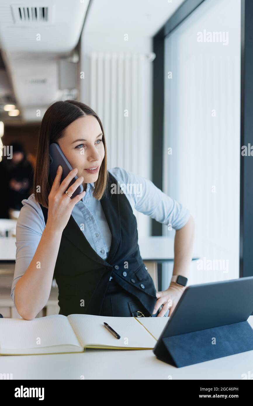 Young charming woman calling with smartphone while sitting alone in ...
