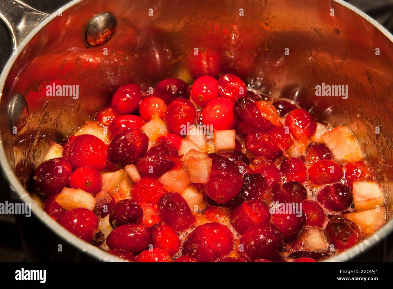 A bubbling pan of fresh cranberries and apples to make cranberry sauce