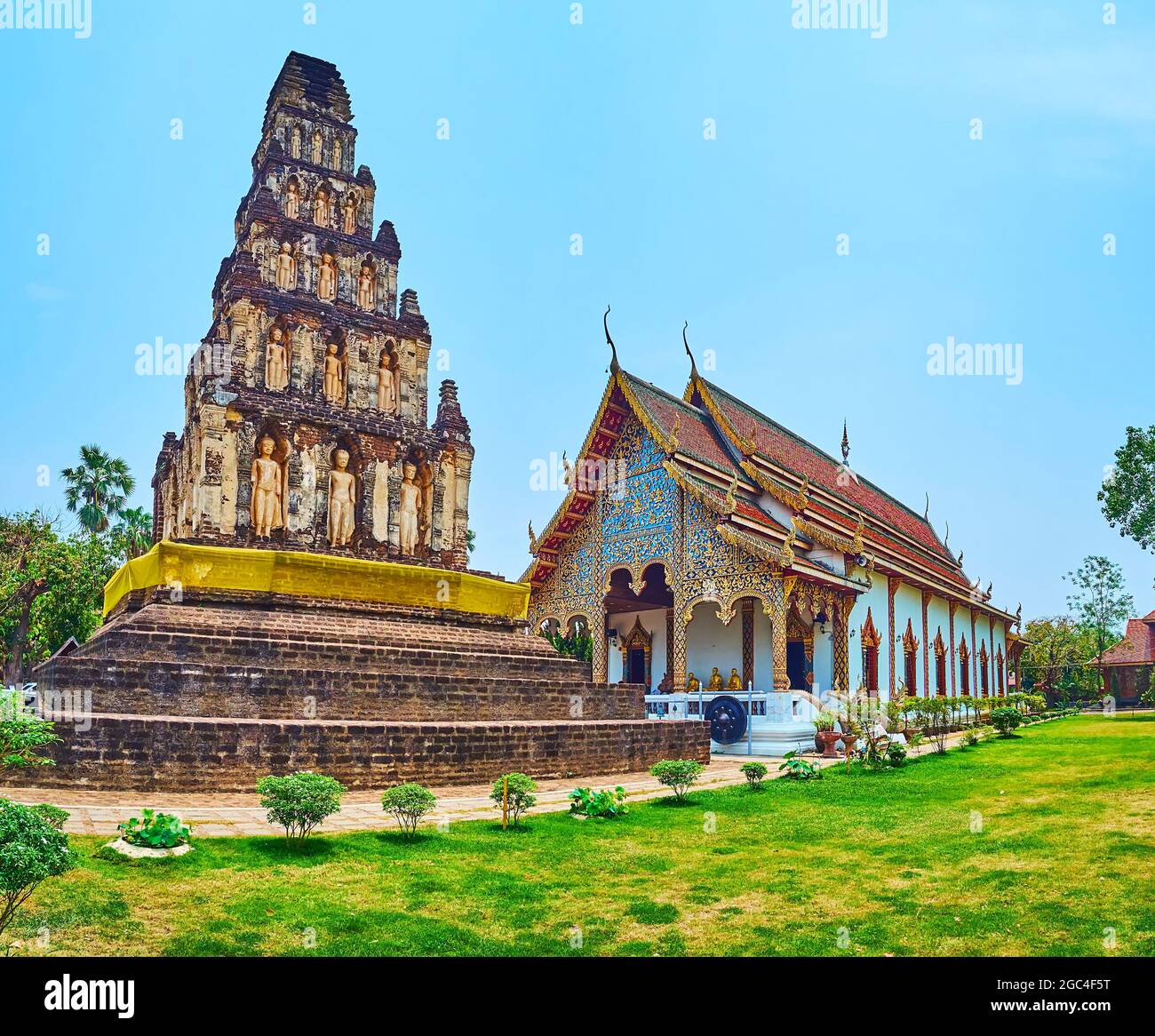 Impressive ancient stupa of Suwan Chedi Jungkote and the ornate Viharn hall of Wat Chammathewi, Lamphun, Thailand Stock Photo