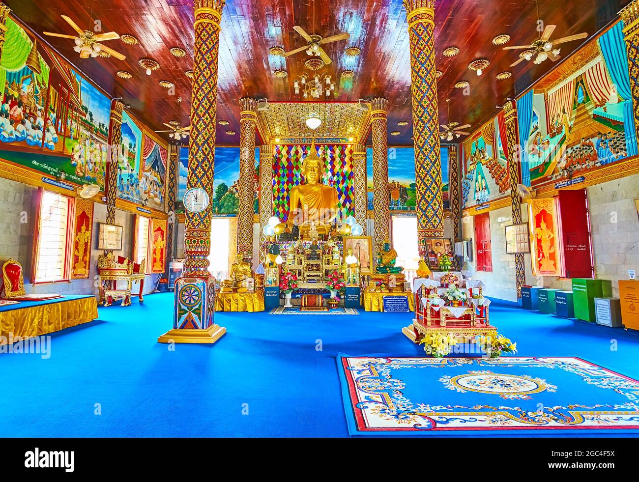 LAMPHUN, THAILAND - MAY 8, 2019: The prayer hall of Wat Chammathewi Assembly Hall (Viharn) with ornate pillars, wooden ceiling and golden Buddha on th Stock Photo
