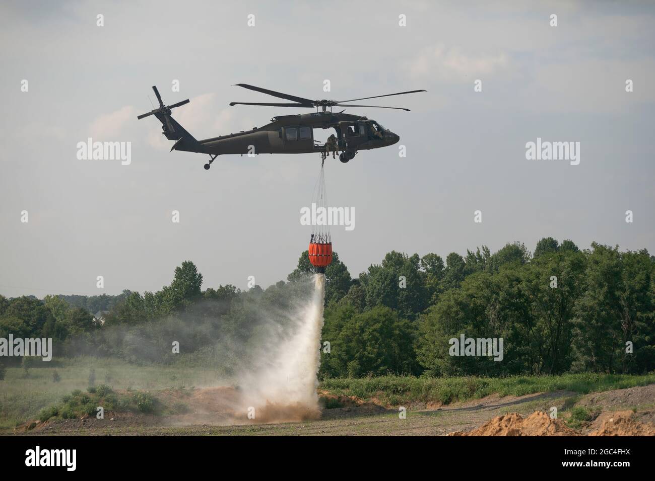 Soldiers of the Kentucky Army National Guard drop water while conducting water bucket training at Wendhell H. Ford Regional Training Center at Greenville, KY on July 19, 2021.  Crewmembers from Bravo Co., 2/147th Assault Helicopter Battalion trains using UH-60 Black Hawks to extinguish forest fires and wild fires to assist local fire departments across Kentucky and neighboring states.  This image was electronically cropped and ethically enhanced to emphasize the subject and does not misrepresent the subject or original image in any way (U.S. Army photo by Staff Sgt. Andrew Dickson). Stock Photo