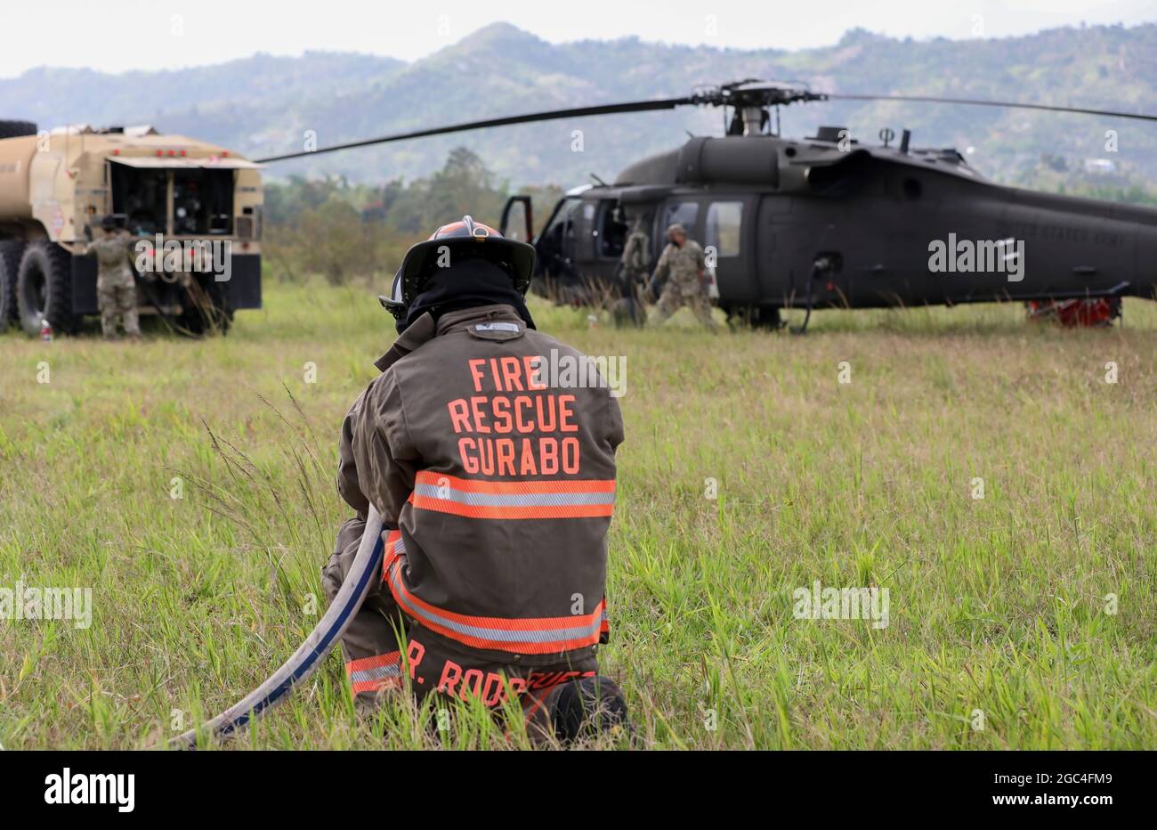 A fireman of the municipality of Gurabo stands ready for a fire emergency during the fueling process of the UH-60 Black Hawk helicopter at Gurabo, Puerto Rico, May 22, 2021. The Governor of Puerto Rico, Pedro Pierluisi, activated the National Guard in support of the Puerto Rico Fire Department to fight fires in the municipalities of Gurabo and Cayey to protect residents' health, well-being, and property. (U.S. Army National Guard photo by Staff Sgt. Marimar Rivera Medina) Stock Photo