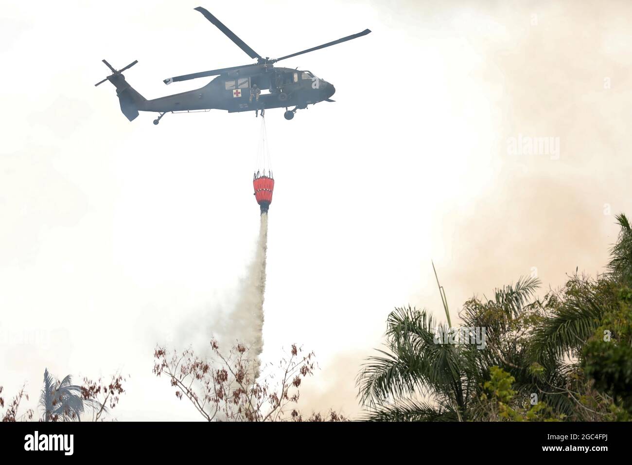 A UH-60 Black Hawk helicopter of Army Aviation of the Puerto A UH-60 Black Hawk helicopter of Army Aviation of the Puerto Army National Guard releases water from a helicopter bucket to fight a fire at Gurabo, Puerto Rico, May 22, 2021. The Governor of Puerto Rico, Pedro Pierluisi, activated the National Guard in support of the Puerto Rico Fire Department to fight fires in Gurabo and Cayey to protect residents' health, well-being, and property. (U.S. Army National Guard photo by Staff Sgt. Marimar Rivera Medina) Stock Photo