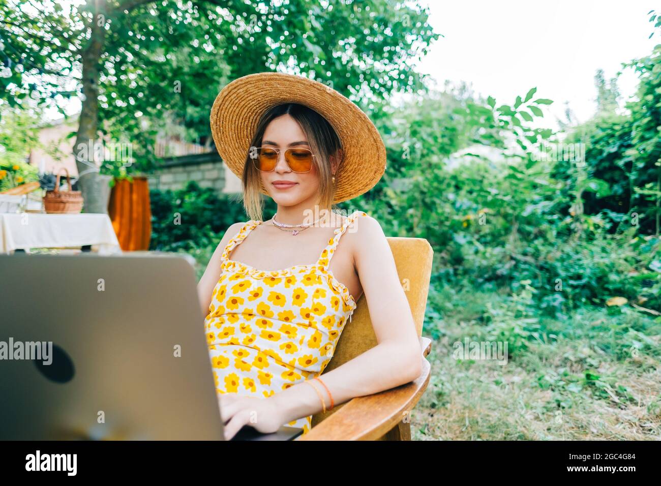 Young caucasian woman using laptop computer outdoor, sitting on a bench ...