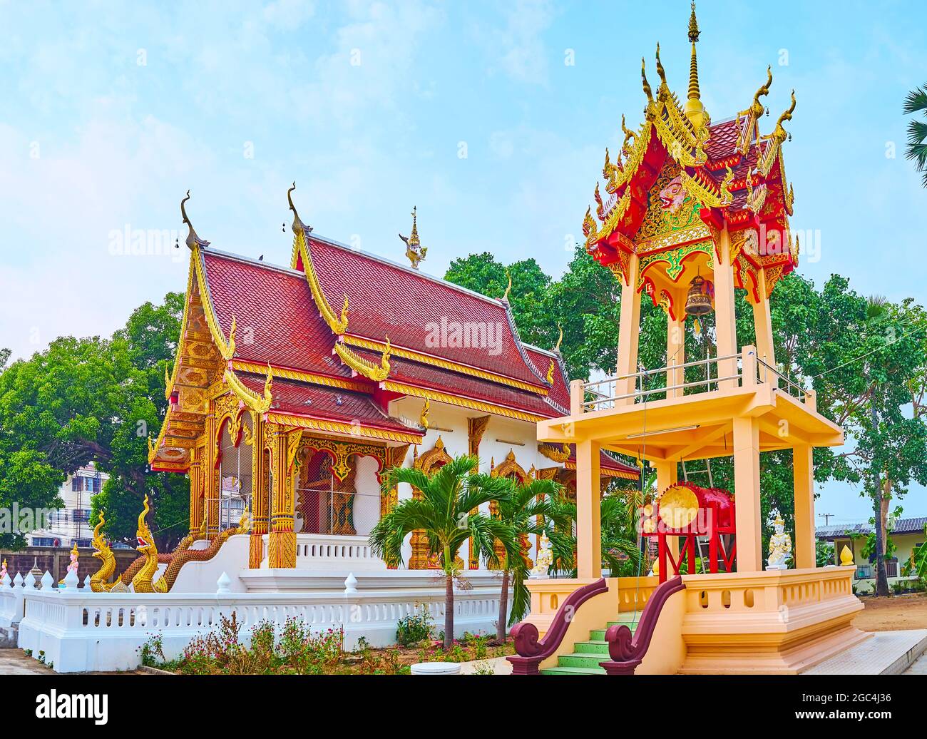The viharn hall with gable (pyathat) roof and the Ho Rakang bell tower with a ritual gong, Wat Sangkharam Temple, Lamphun, Thailand Stock Photo