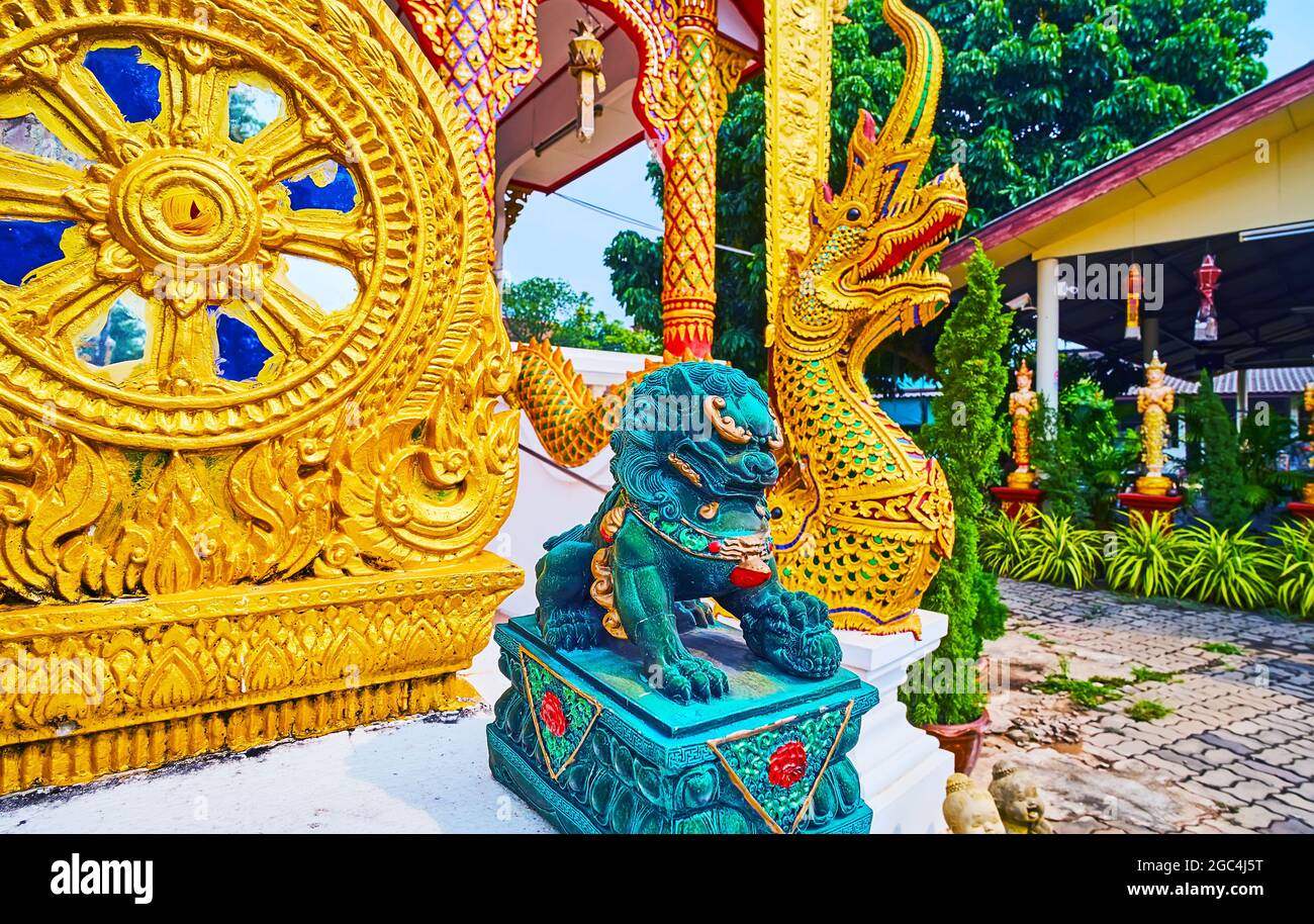 The gilt sculpture of Wheel of Dharma, small green Chinese Imperial Guardian Lion, also named Foo Dog and Naga serpent, located in front of Wat Thong Stock Photo