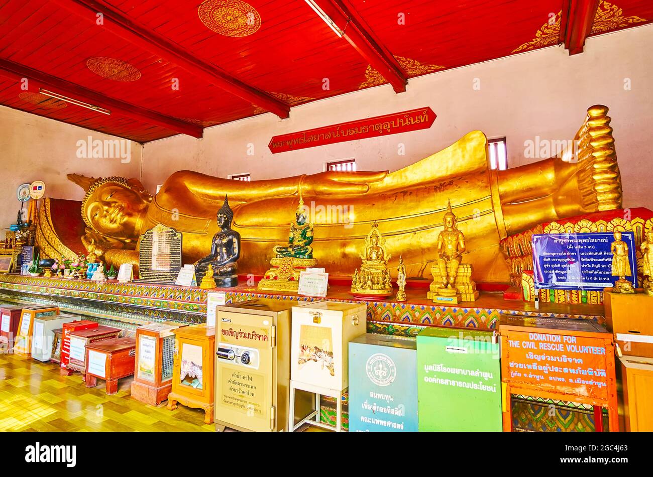 LAMHPUN, THAILAND - MAY 8, 2019: Interior of the Image House with large golden Reclining Buddha and small imagesof Buddha in front of it, Wat Phra Tha Stock Photo