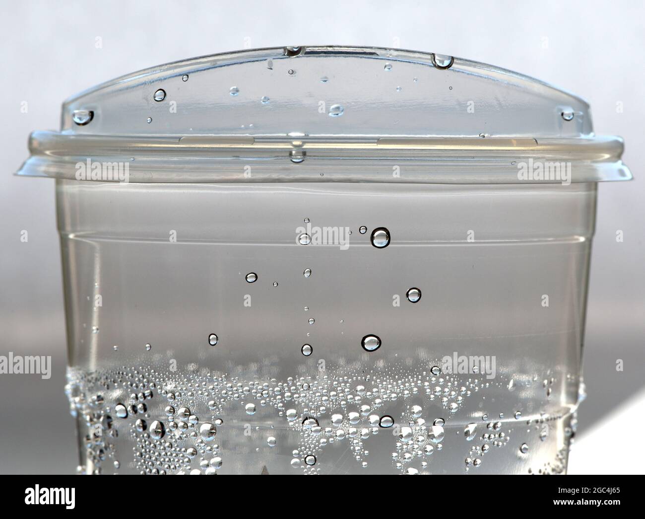 A single use disposable clear plastic cup filled with ice water has ...