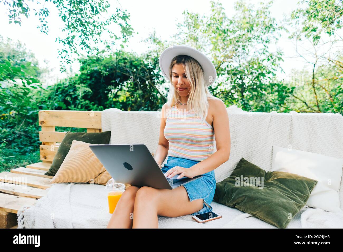 Young caucasian woman using laptop computer outdoor, sitting on a bench ...