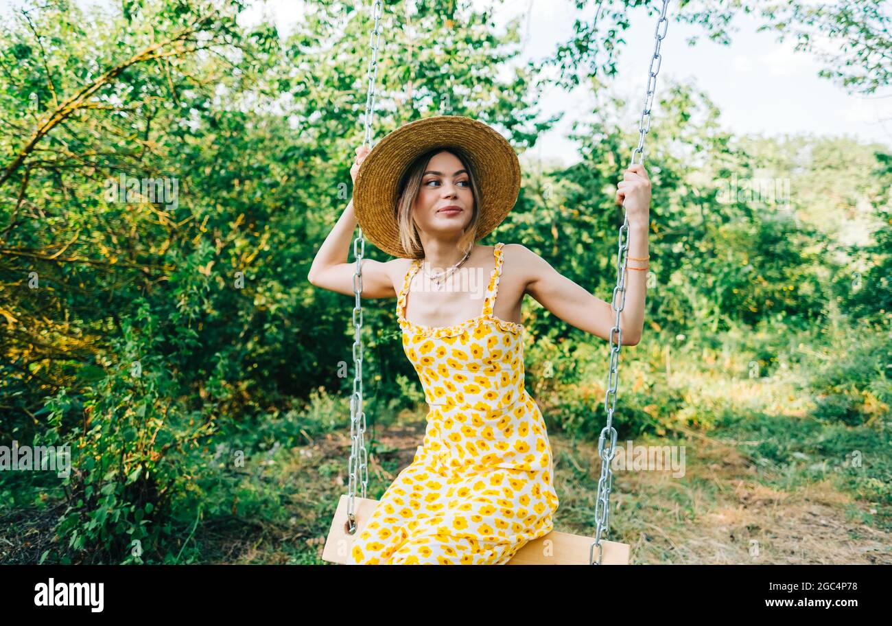 Portrait of attractive young woman in straw hat outdoors in summer ...