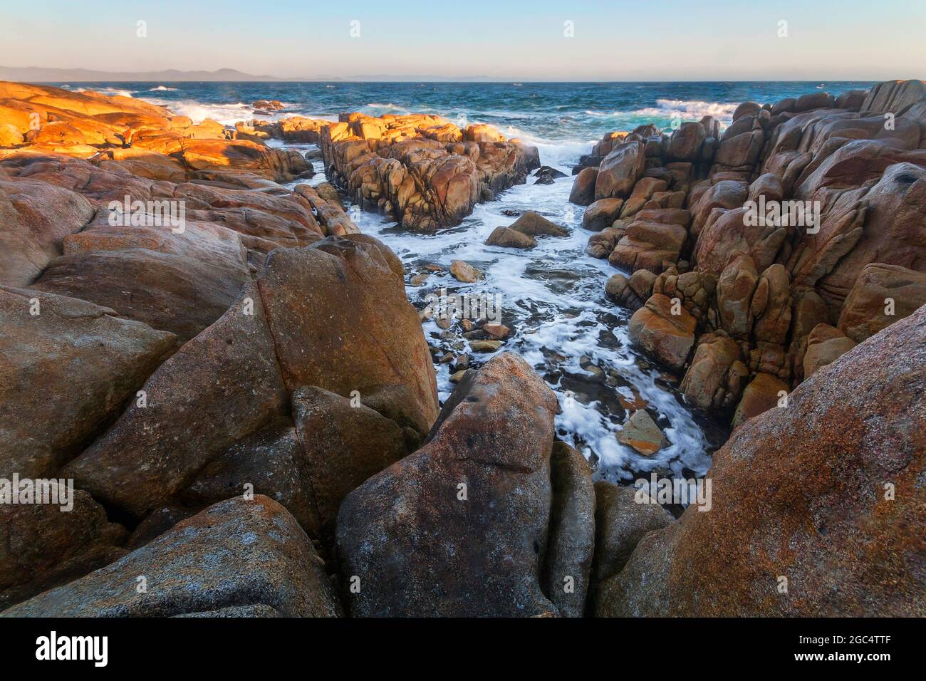 rocks and sunlight next to the water on the coast Stock Photo