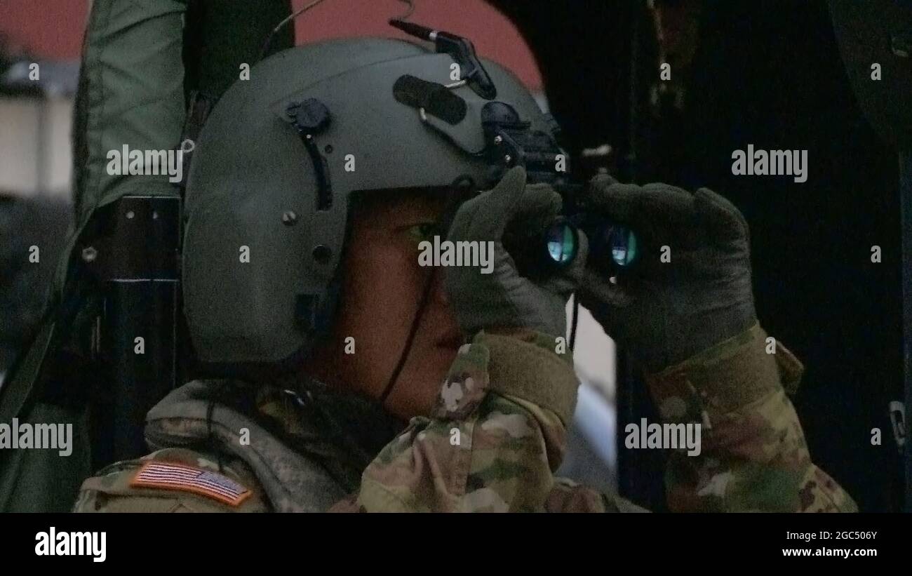 U.S. Army Chief Warrant Officer 1 Ge Xiong of the California Army National Guard, crew chief aboard a UH-60 Black Hawk, adjusts his night vision goggles (NVG) prior to a Sept. 8, 2020, rescue mission in the Sierra National Forest during the Creek Fire. Xiong was the crew chief during a daring mission to rescue people who were trapped by the fast-paced Creek Fire in Fresno County, California. The fire ignited Sept. 4 but in two days devoured more than 80,000 acres. Stock Photo