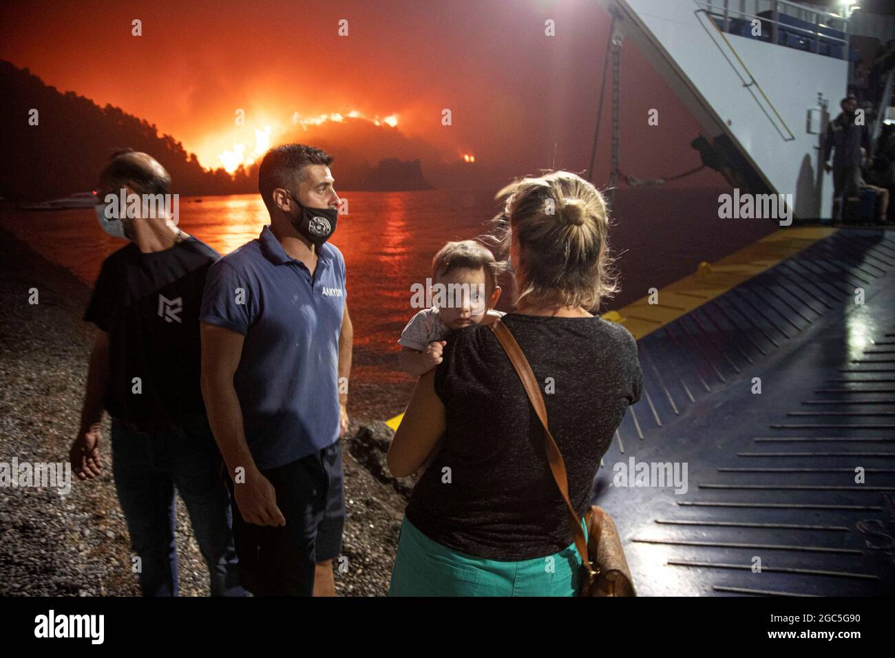 People board a ferry during evacuation as a wildfire burns in the village of Limni, on the island of Evia, Greece, August 6, 2021. Picture taken August 6, 2021. REUTERS/Nicolas Economou Stock Photo