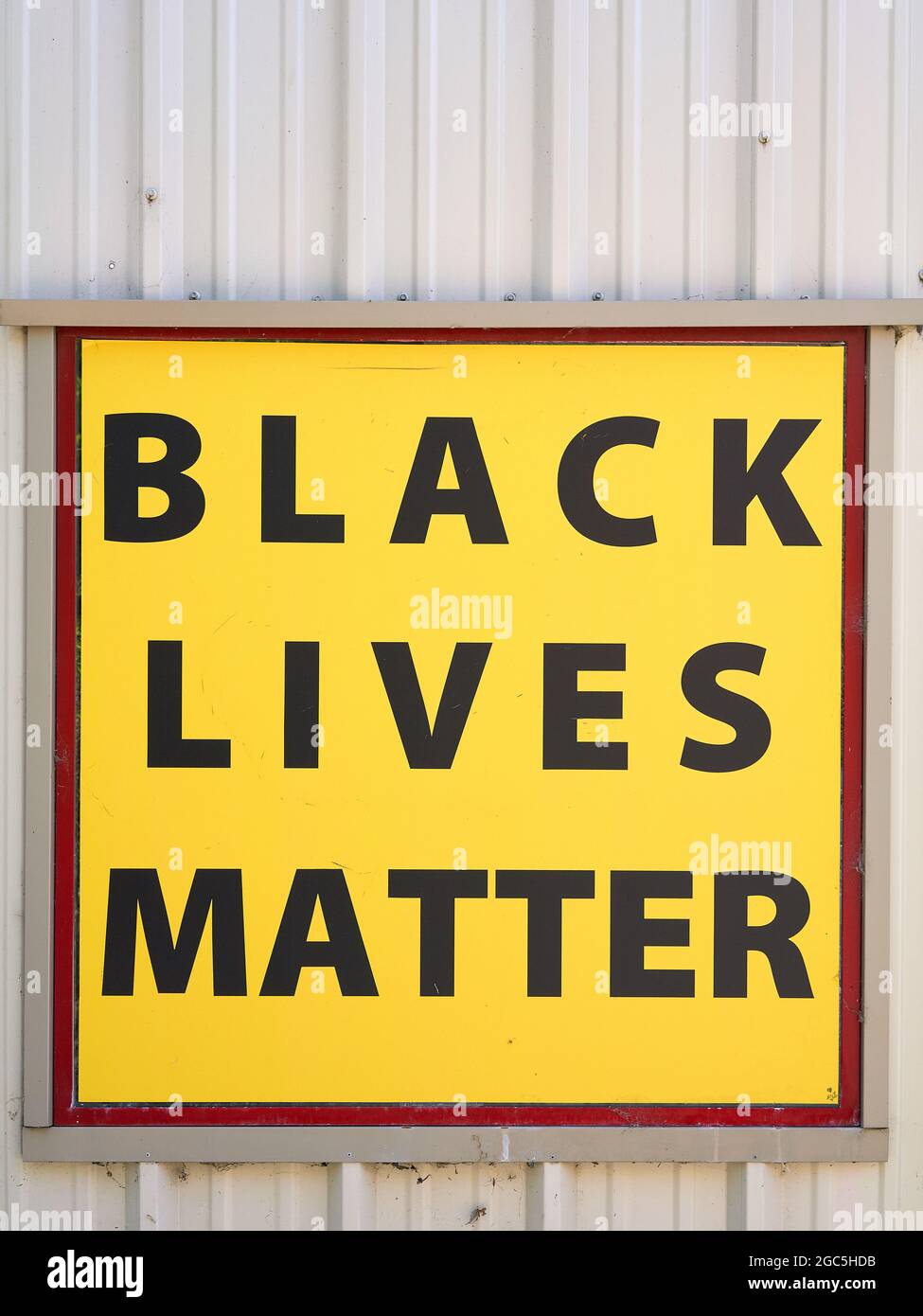 Black Lives Matter sign on yellow background on metal building wall. Stock Photo