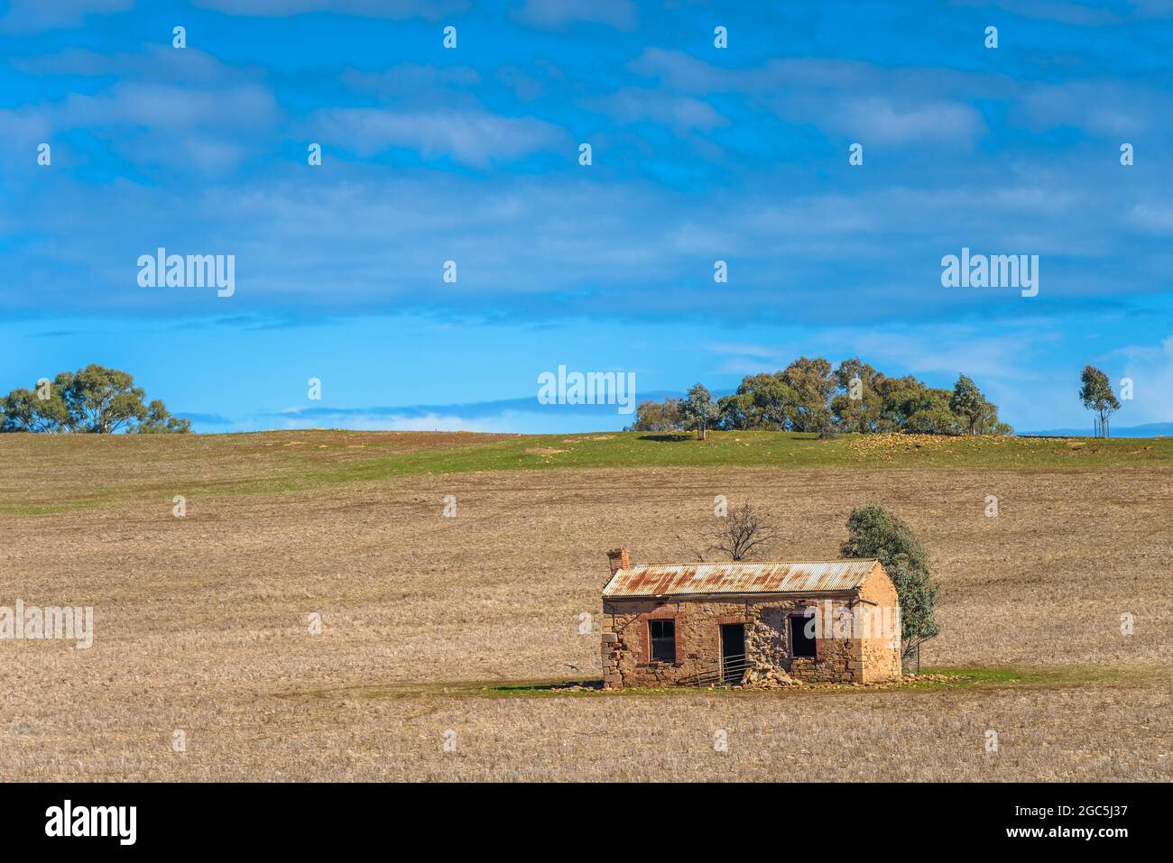 An abandoned heritage listed pioneer, stone farmhouse sits on a ploughed field on a gentle sloping hillside near Burra in South Australia. Stock Photo