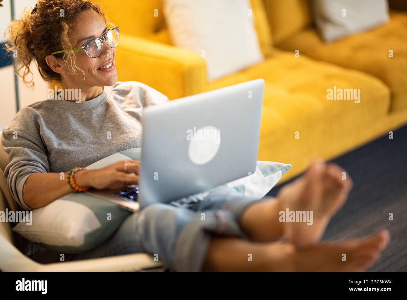 Adult caucasian woman smile and use laptop computer sitting comfy ...