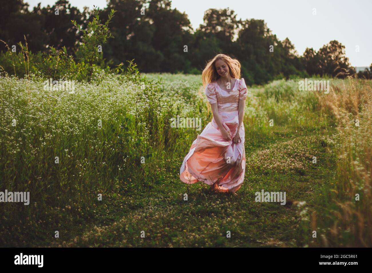 girl standing in the field in a pink dress Stock Photo - Alamy