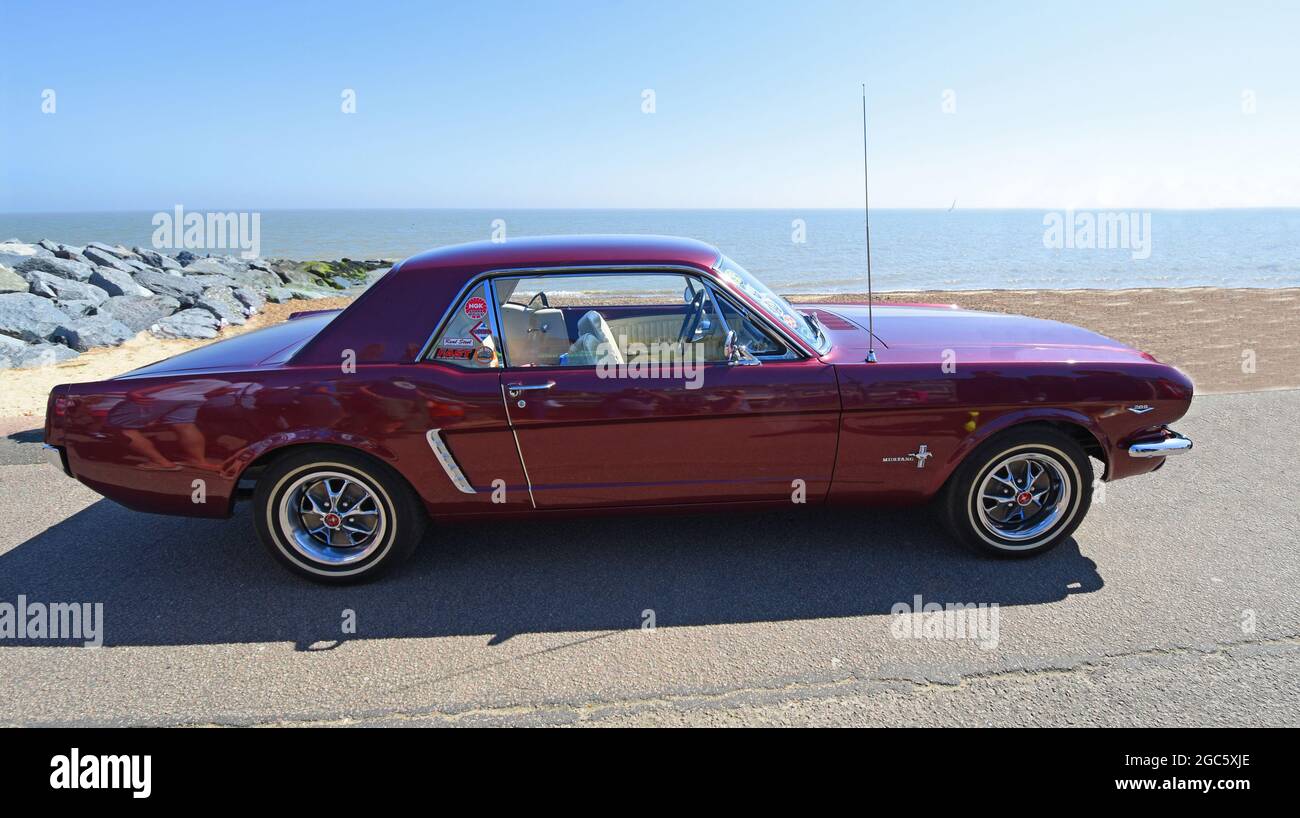 Classic Purple Ford Mustang parked on seafront beach and sea in background. Stock Photo