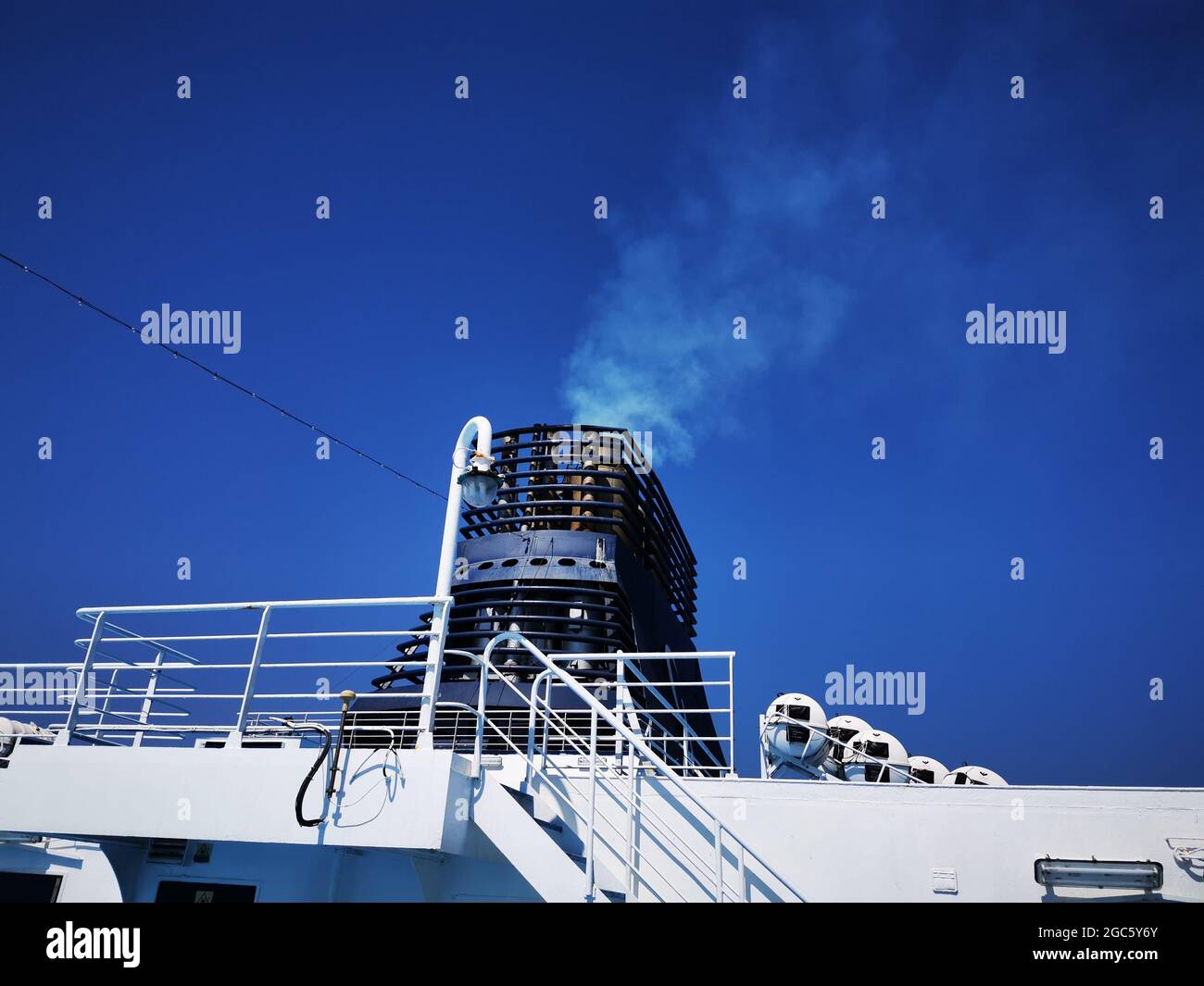 Low angle shot of a ship chimney top with white smoke out in the blue ...
