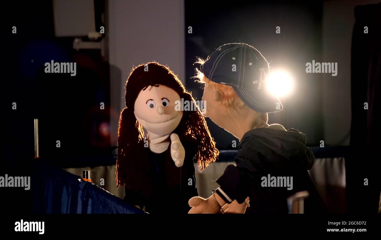 Puppet girl speaking with puppet boy during the performance. In the backgrounds - lighting equipment Stock Photo