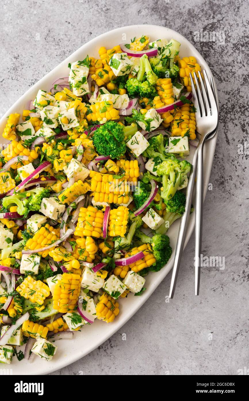 Salad with young corn and cheese, onion and broccoli with dill and