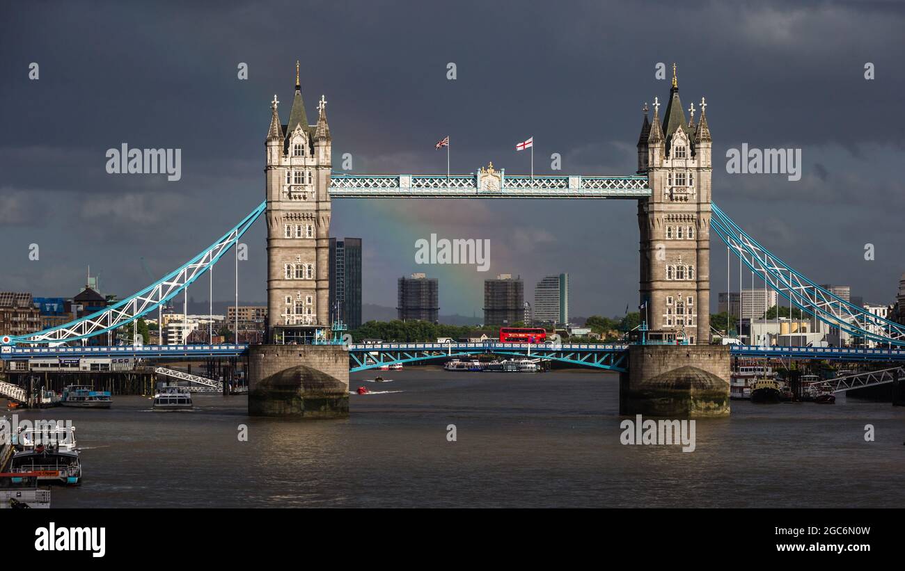 Dark clouds and a red London bus, and a beautiful rainbow over iconic Tower Bridge in London. Stock Photo
