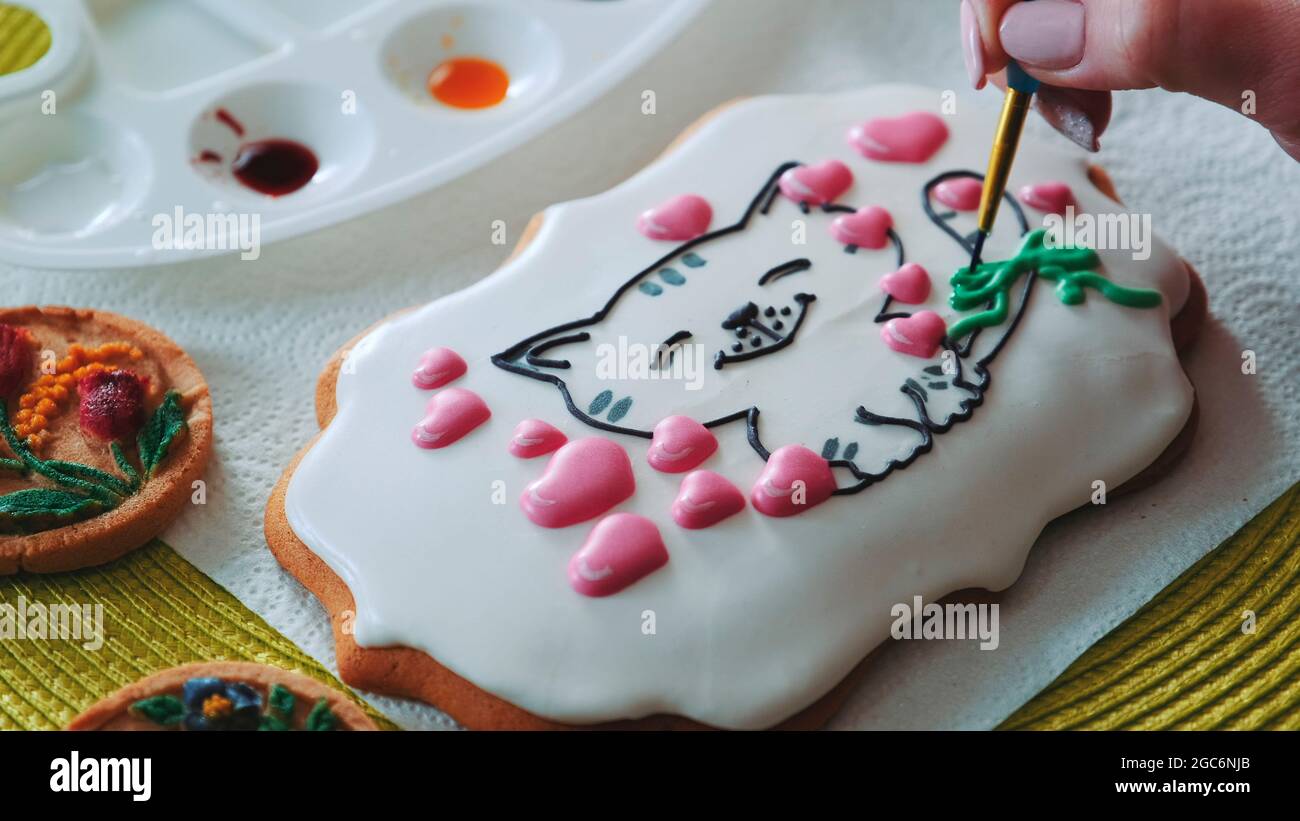 Cookie decorating masterclass with royal icing. Bakery worker decorating gingerbread cookies. Stock Photo