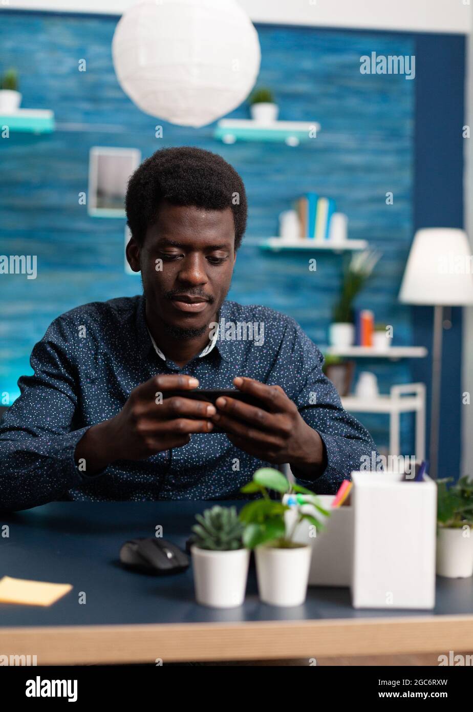 Black african american man using a smartphone at home working on social ...