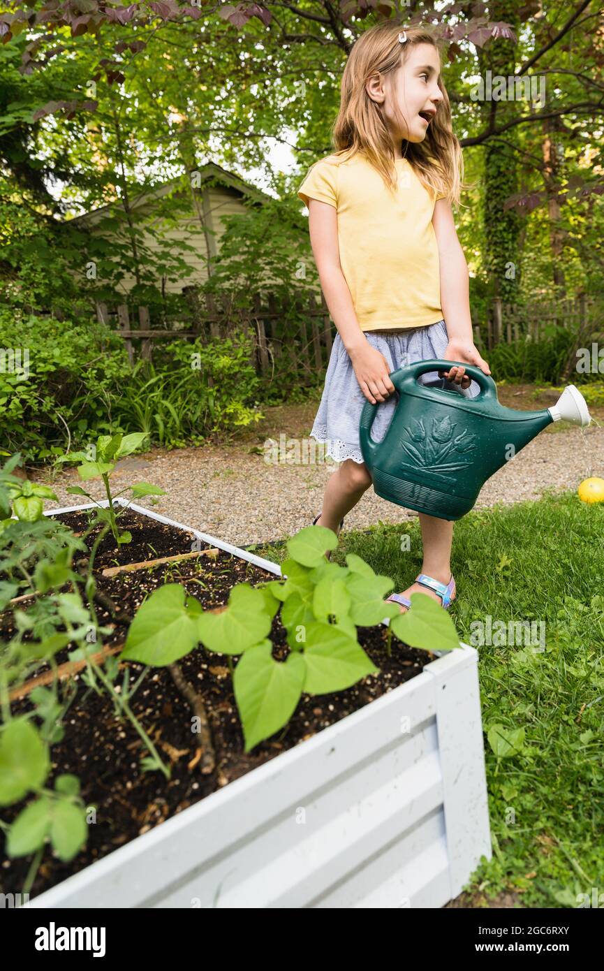 Girl holding watering can in garden Stock Photo