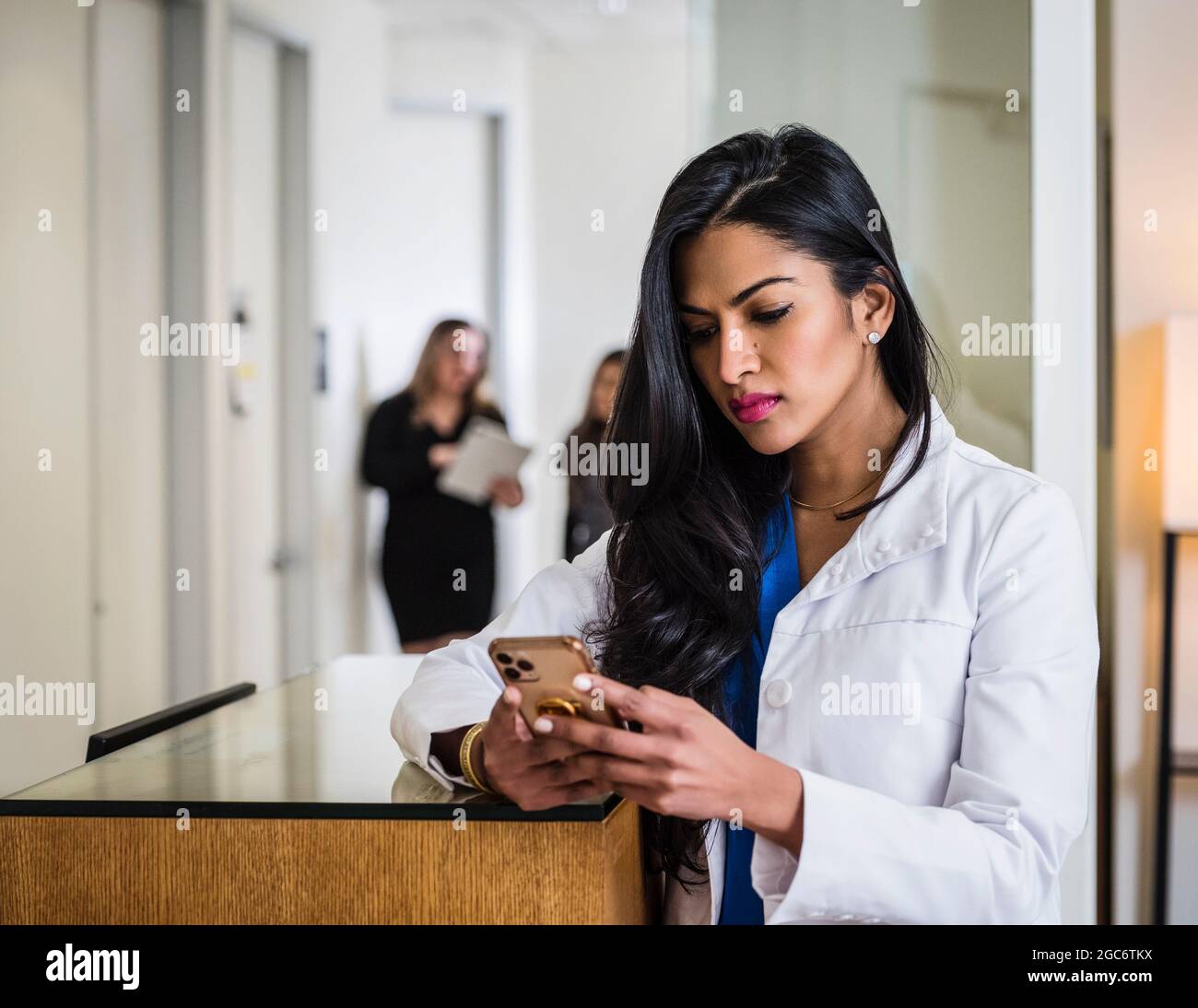 Female doctor with smart phone at reception desk Stock Photo