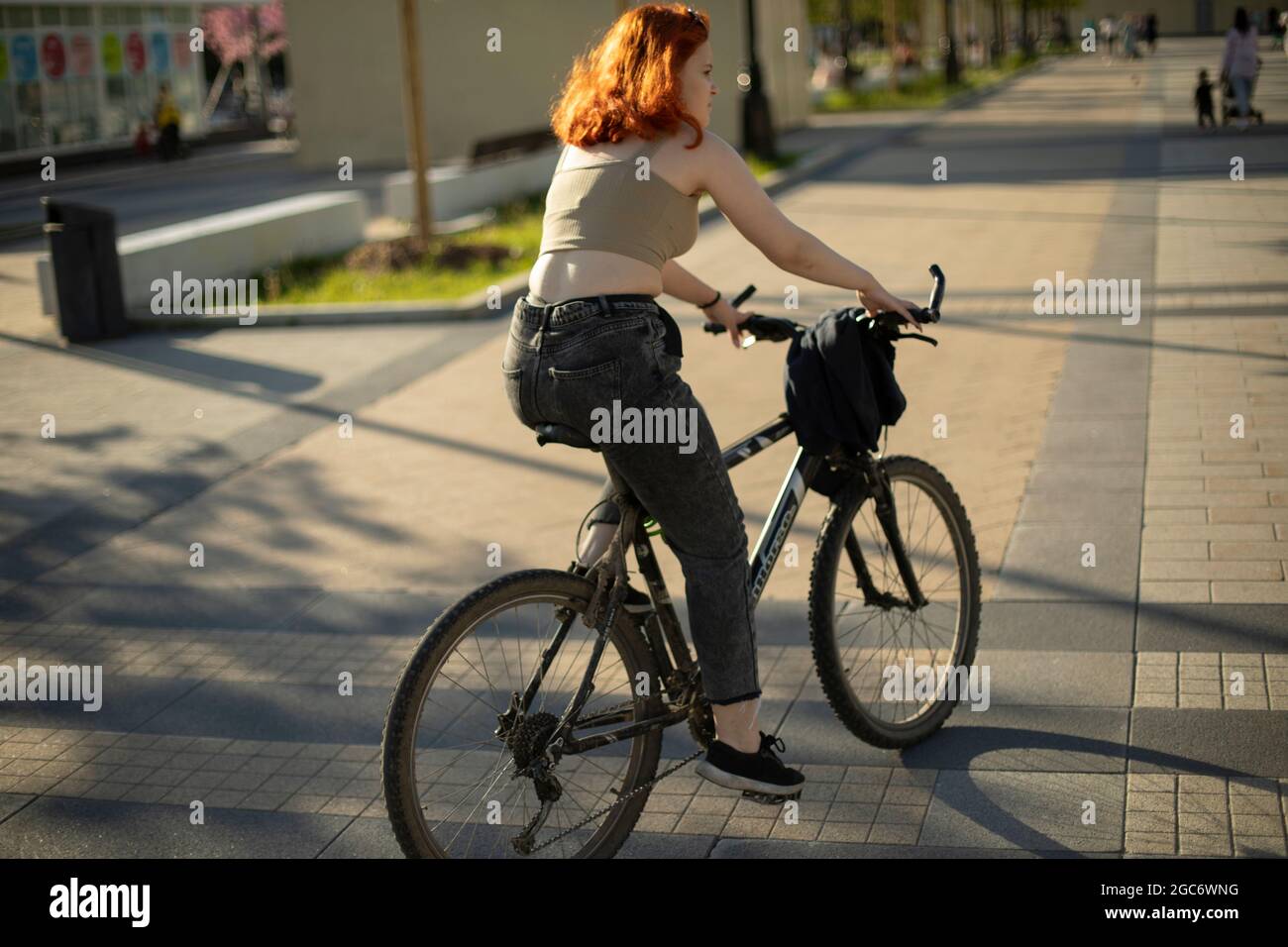 A girl rides a bike. Walking around the city by bicycle. A girl with ...