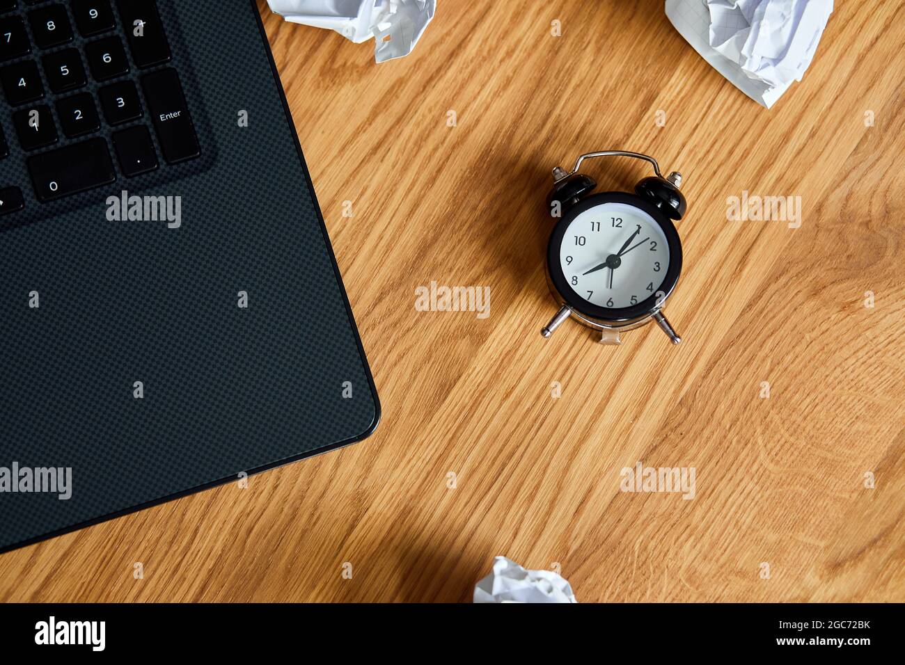 Top view of wooden office desk with clock,, notebook, crumpled paper ...