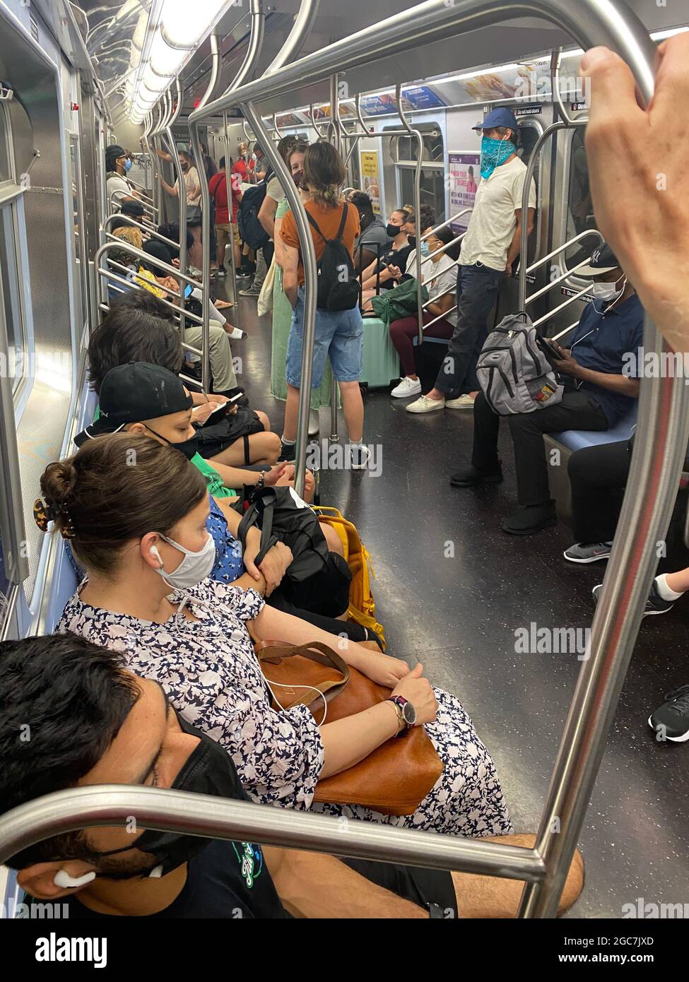 Masked commuters ride a New York City subway train in July 2021 when it was hoped the pandemic would be over but it seems to continue. People are tired of living on half breath. Stock Photo
