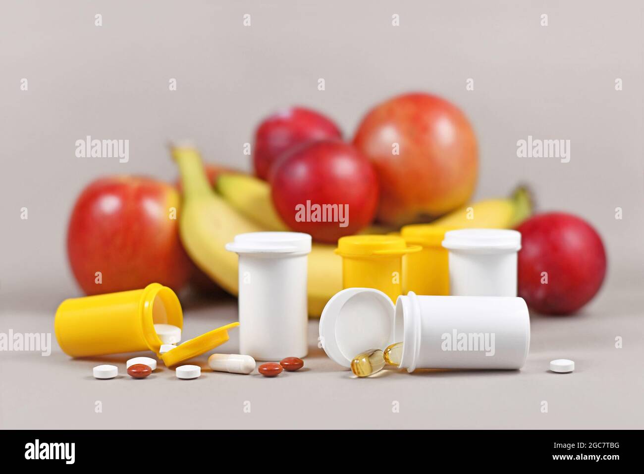 Food nutrition supplement capsules and pills with with plastic bottles in front of fruits Stock Photo