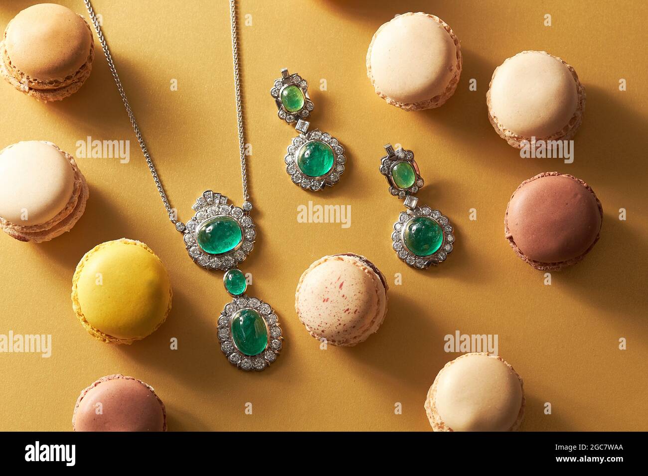High angle shot of a necklace and earrings with blue beads next to delicious macarons Stock Photo
