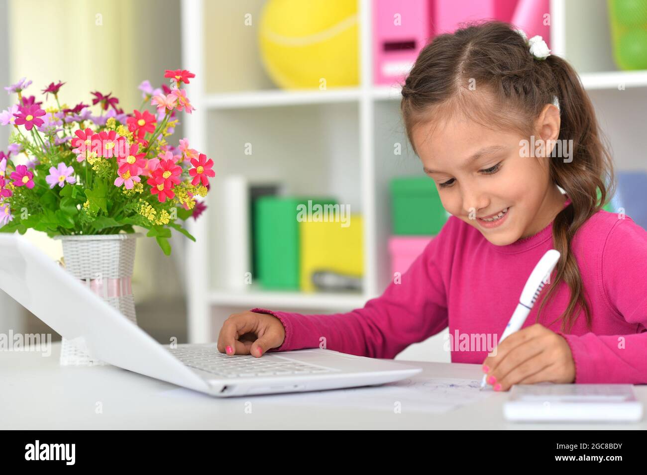 Porait of cute girl using laptop at home at desk Stock Photo - Alamy
