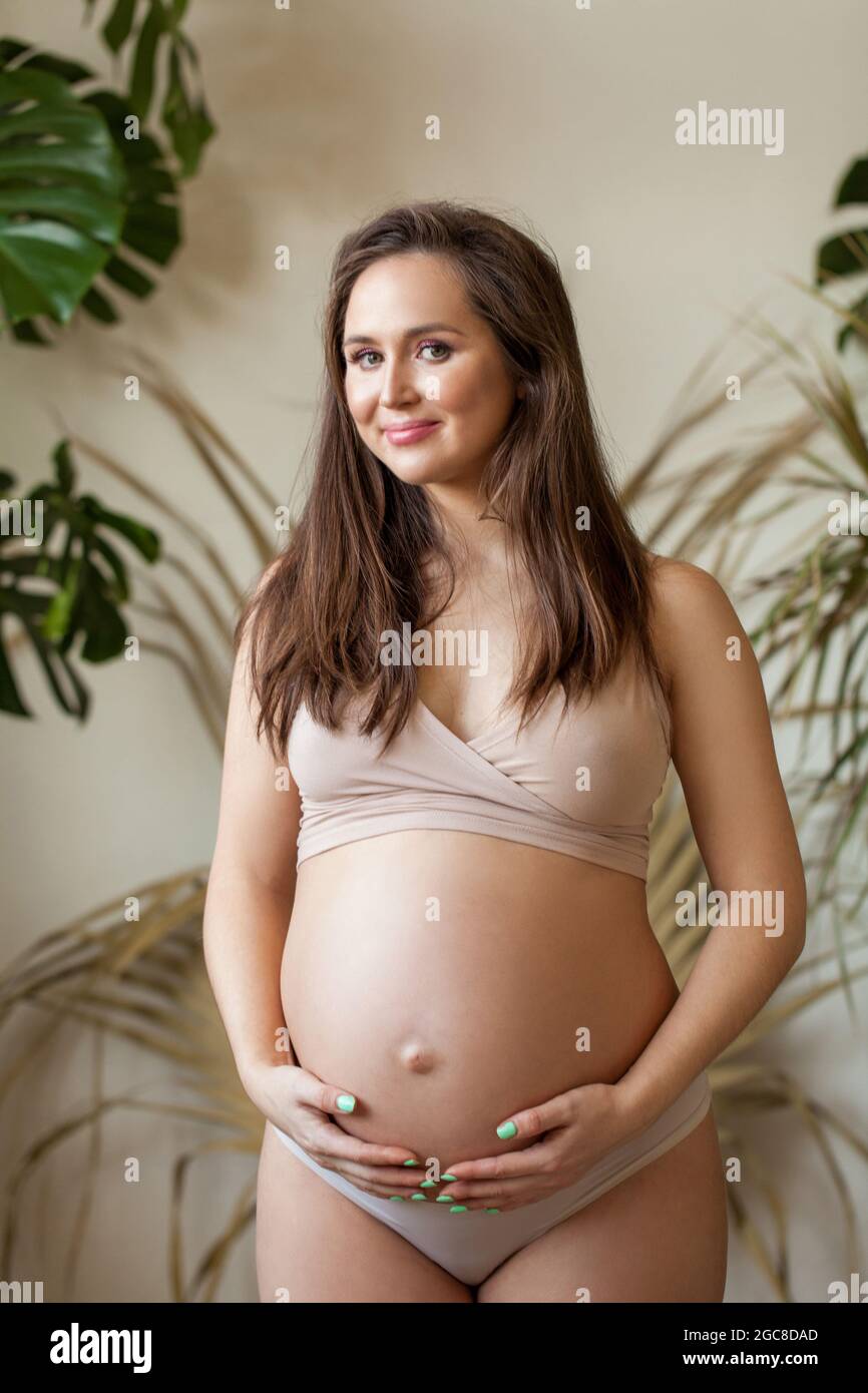 Cute smiling woman pregnant. Friendly pregnant female model with long hair wearing sports swimsuit Stock Photo