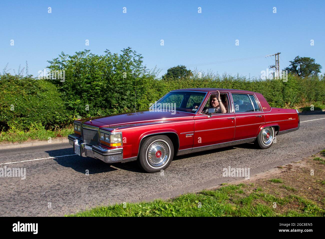 1983 80s eighties red AmericanCadillac 4100cc 4dr sedan en-route to Capesthorne Hall classic July car show, Cheshire, UK Stock Photo