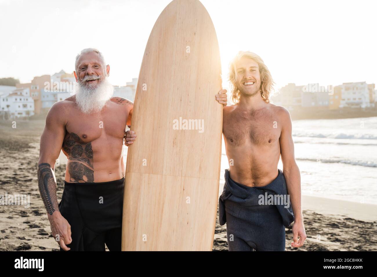 Multigenerational surfer father and son enjoying surf extreme sport session in summer vacation - Focus on senior man Stock Photo