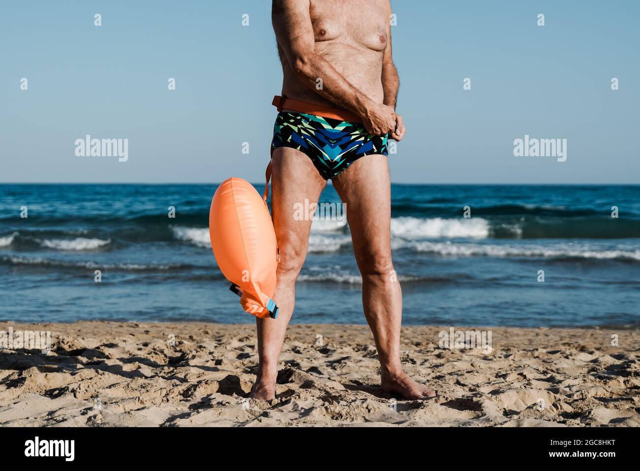 Sport swimmer senior man training to swim open water triathlon with beach on background - Elderly and healthy lifestyle Stock Photo