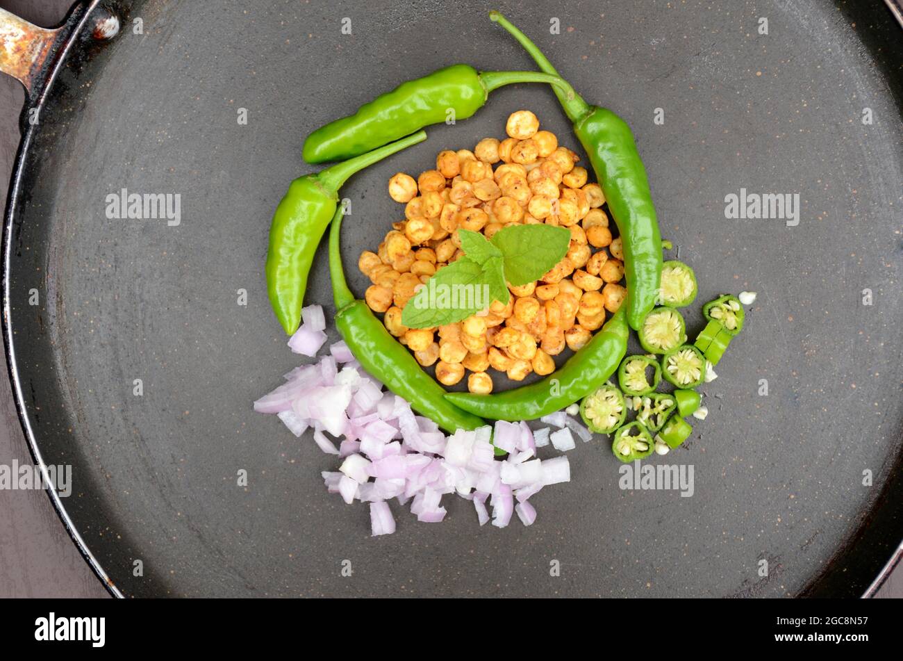 closeup the fried yellow bengal gram lentils with mint ,green chilly, sliced onion, over out of focus black background. Stock Photo