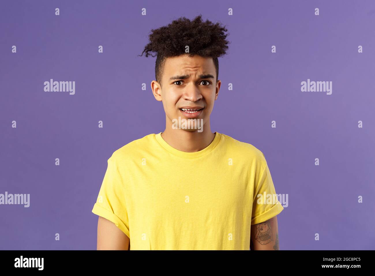 Close-up portrait of awkward and embarrassed young hispanic guy looking ...
