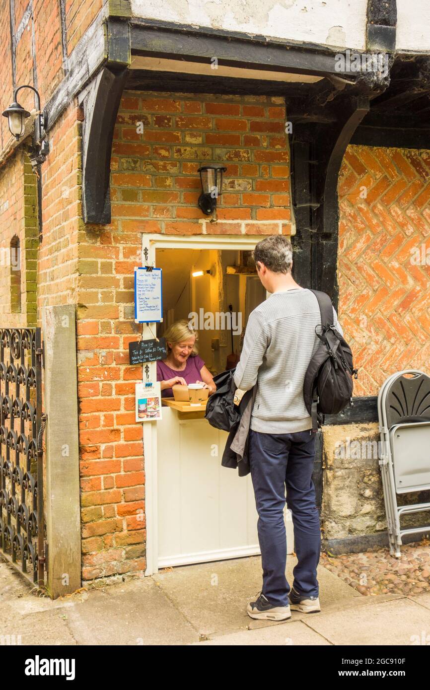 Man buying drinks through a serving hatch at  Dorchester Abbey Tea Rooms Dorchester on Thames Oxfordshire England Stock Photo