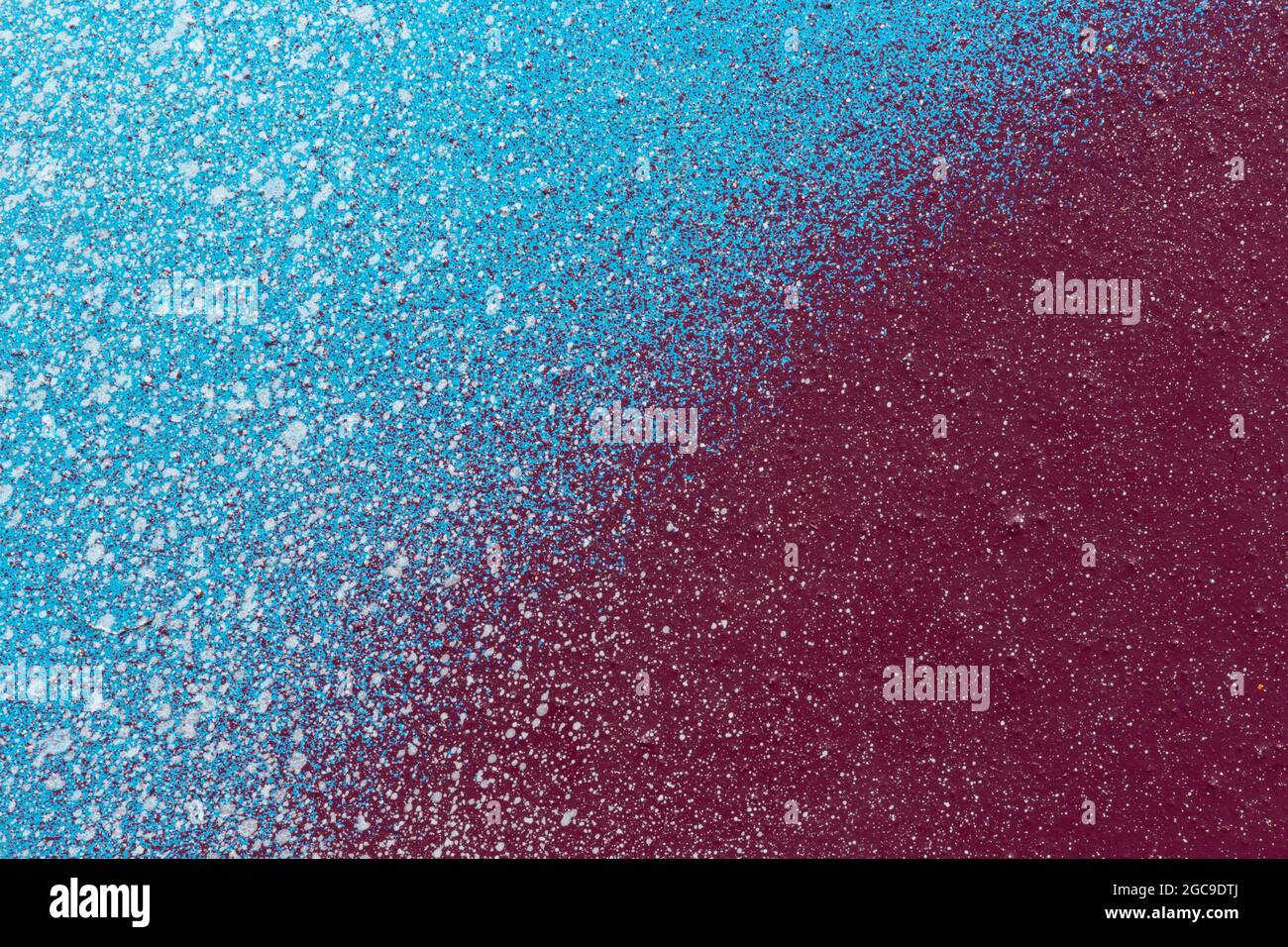 Macro close-up of a light blue and burgundy red spray paint with white splashes. Abstract textured splattered graffiti background with copy space. Stock Photo